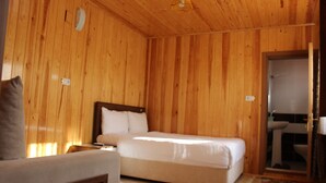 A wooden-paneled room with a bed, a bedside table, and a bathroom visible through an open door. - Uzungol Adiloglu Apart (Çaykara)