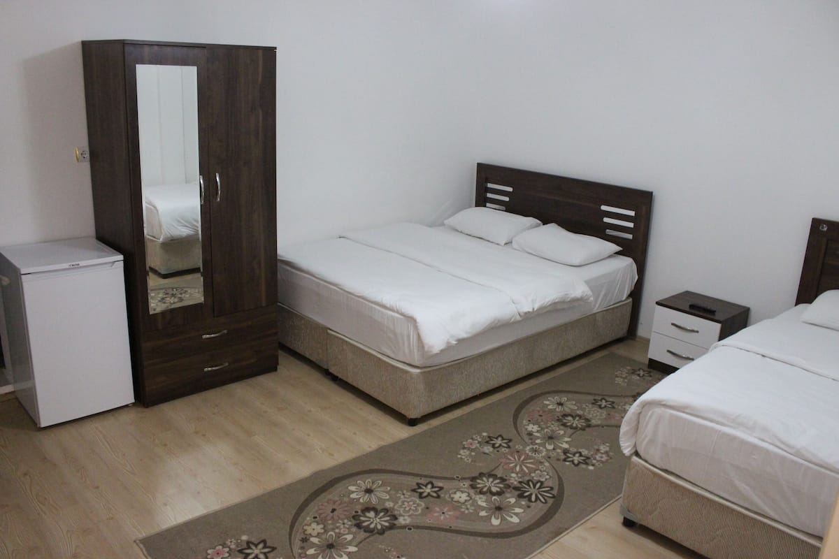 A bedroom with a bed, a wardrobe, a nightstand, and a small table.
