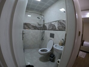 Ein modernes Badezimmer mit einer begehbaren Glasdusche, einer Toilette und einem Waschbecken.