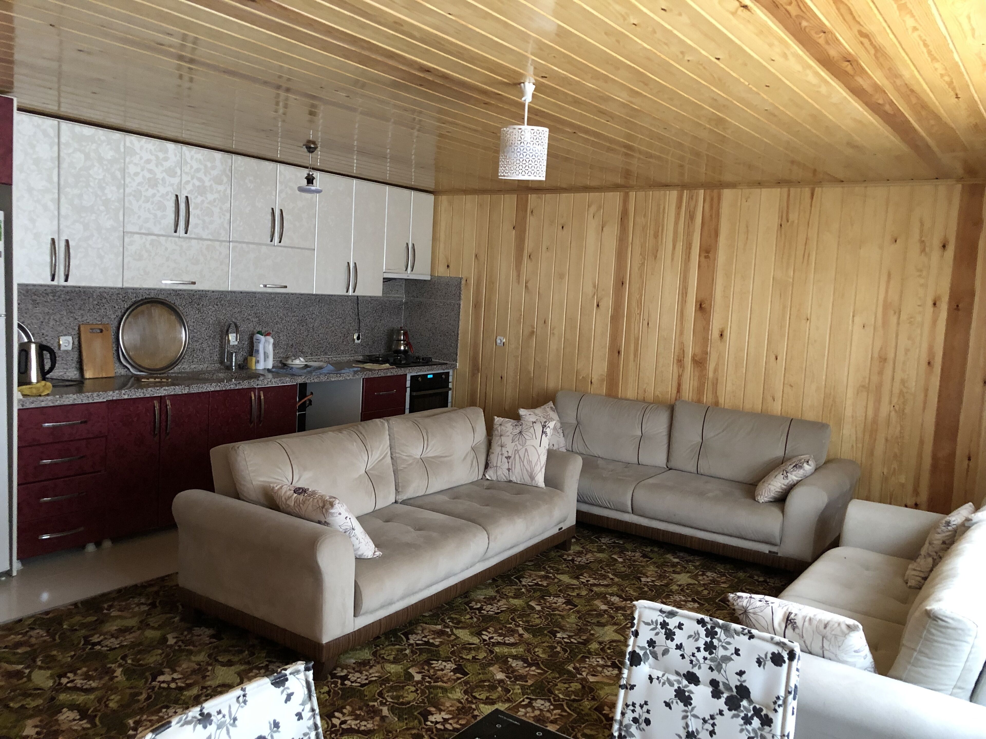 A cozy living area with a sofa set, a kitchen with granite countertops, and a patterned rug.