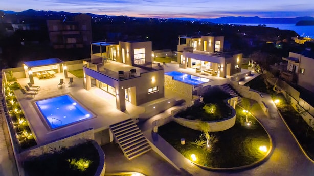Una villa moderna con due piscine, un giardino curato e vista mare.