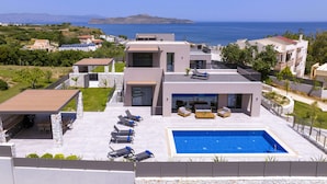Una villa moderna con piscina, area salotto all'aperto e vista sul mare.