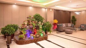 A modern lobby with a central water feature, seating area, and potted plants. - Huayi Selected Hotel (Hohhot)