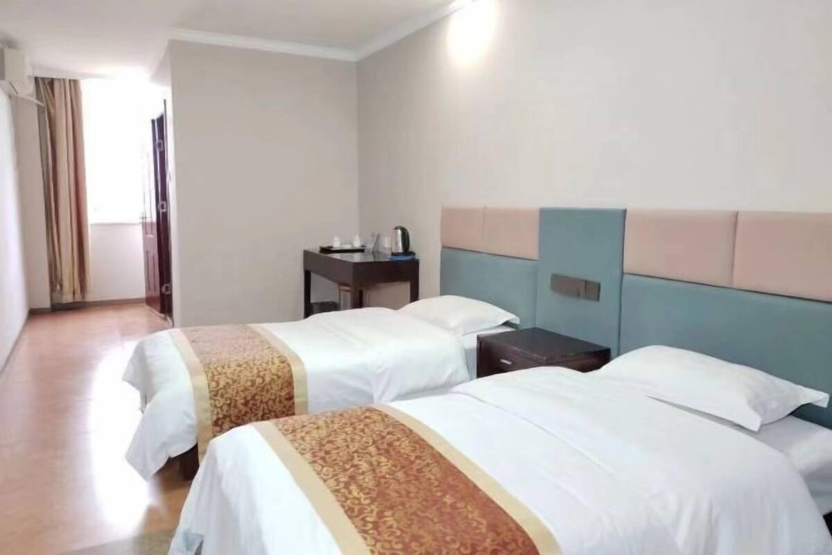 Une chambre d’hôtel avec deux lits, une table de chevet et une petite table avec une bouilloire.