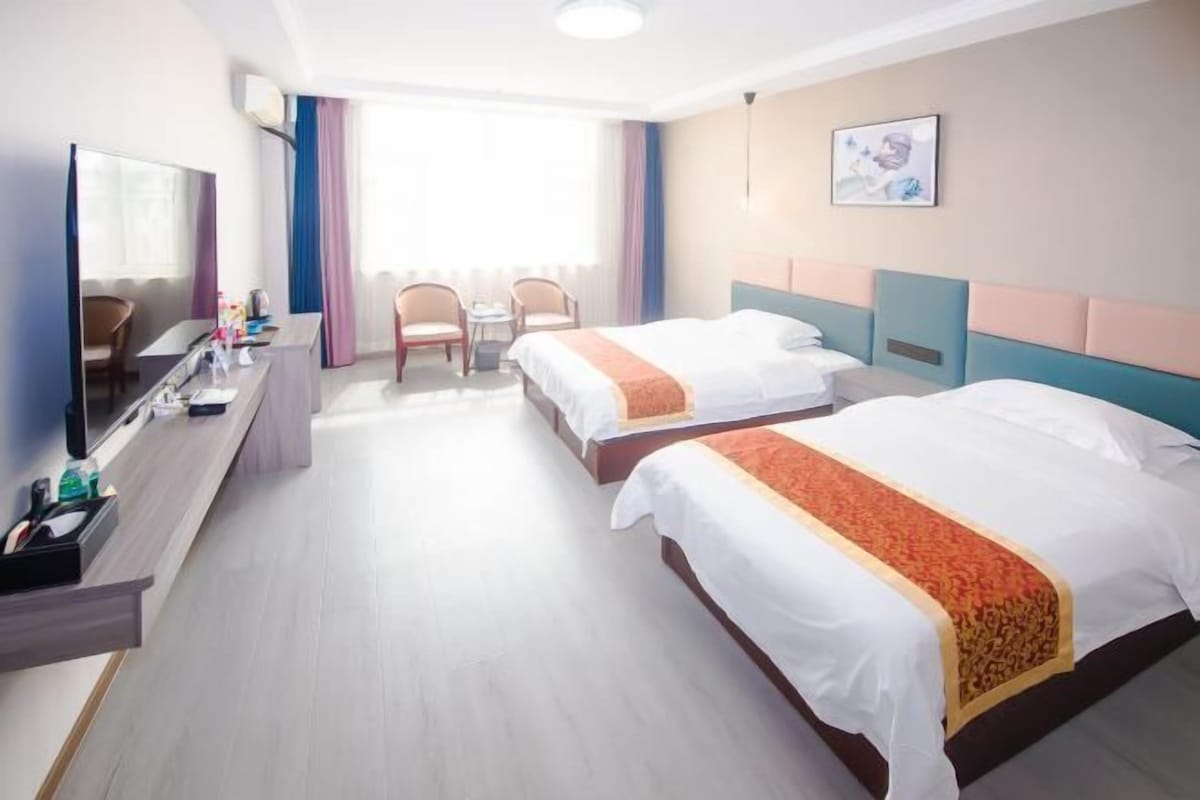 Een hotelkamer met twee bedden, een bureau met spiegel en een kleine tafel met stoelen.