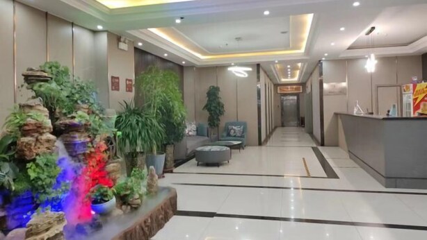 A hotel lobby with a reception desk, seating area, and a decorative rock garden with plants. - Huayi Selected Hotel (Hohhot)