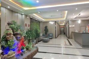 A hotel lobby with a reception desk, a seating area, and a decorative plant arrangement. - Huayi Selected Hotel (Hohhot)