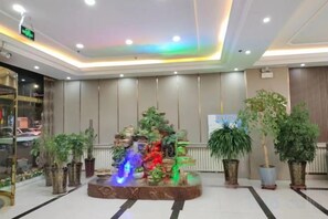 A lobby with a water feature, potted plants, and a reception desk. - Huayi Selected Hotel (Hohhot)