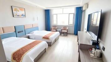 Habitación de hotel con dos camas, un escritorio, una silla, un televisor y una ventana con cortinas.