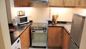 A compact kitchen with a microwave, toaster, stove, and refrigerator. - KSLV - Furnished Studio (Dubai)
