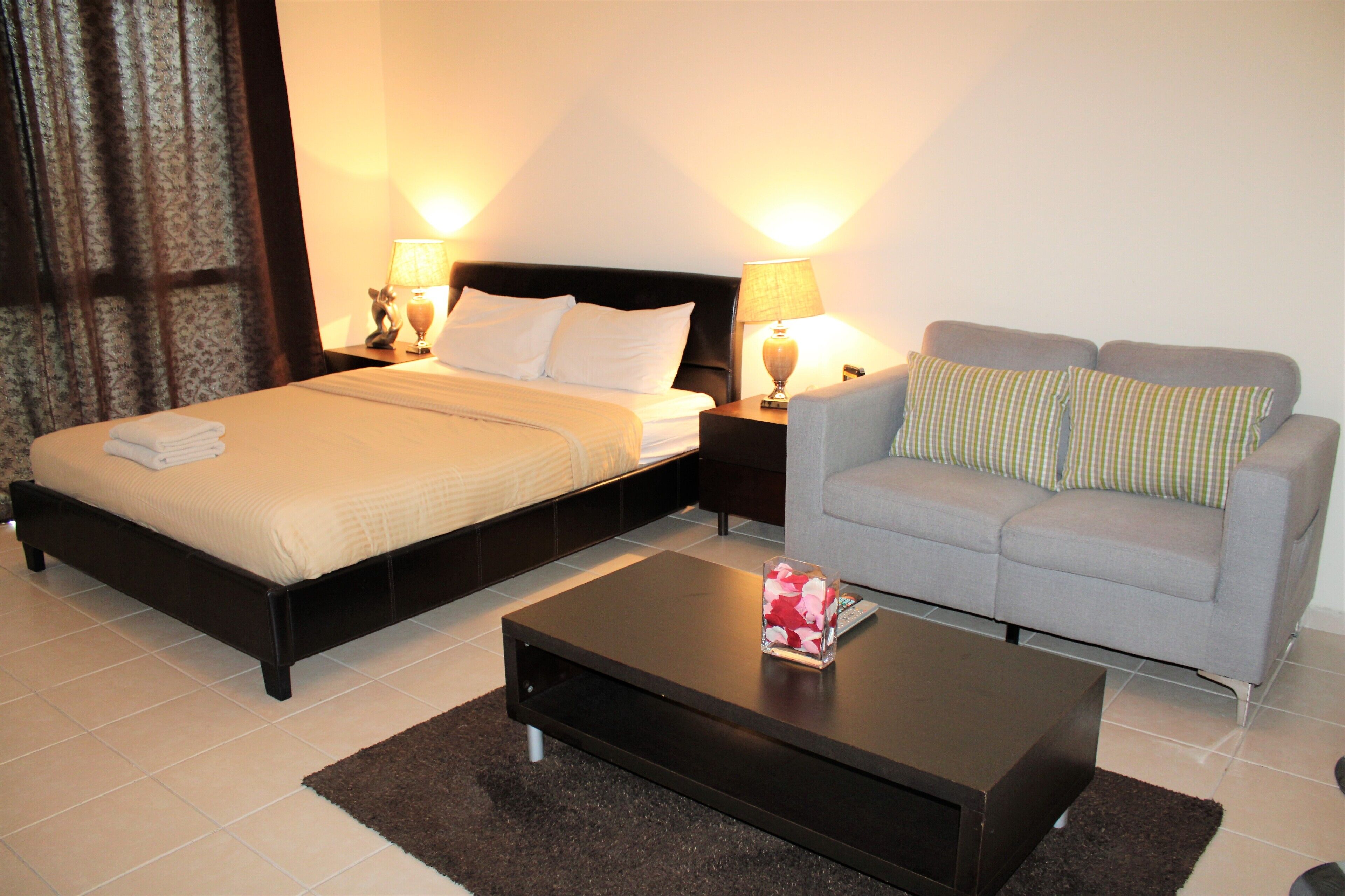 A hotel room with a bed, a sofa, a coffee table, and two bedside lamps.