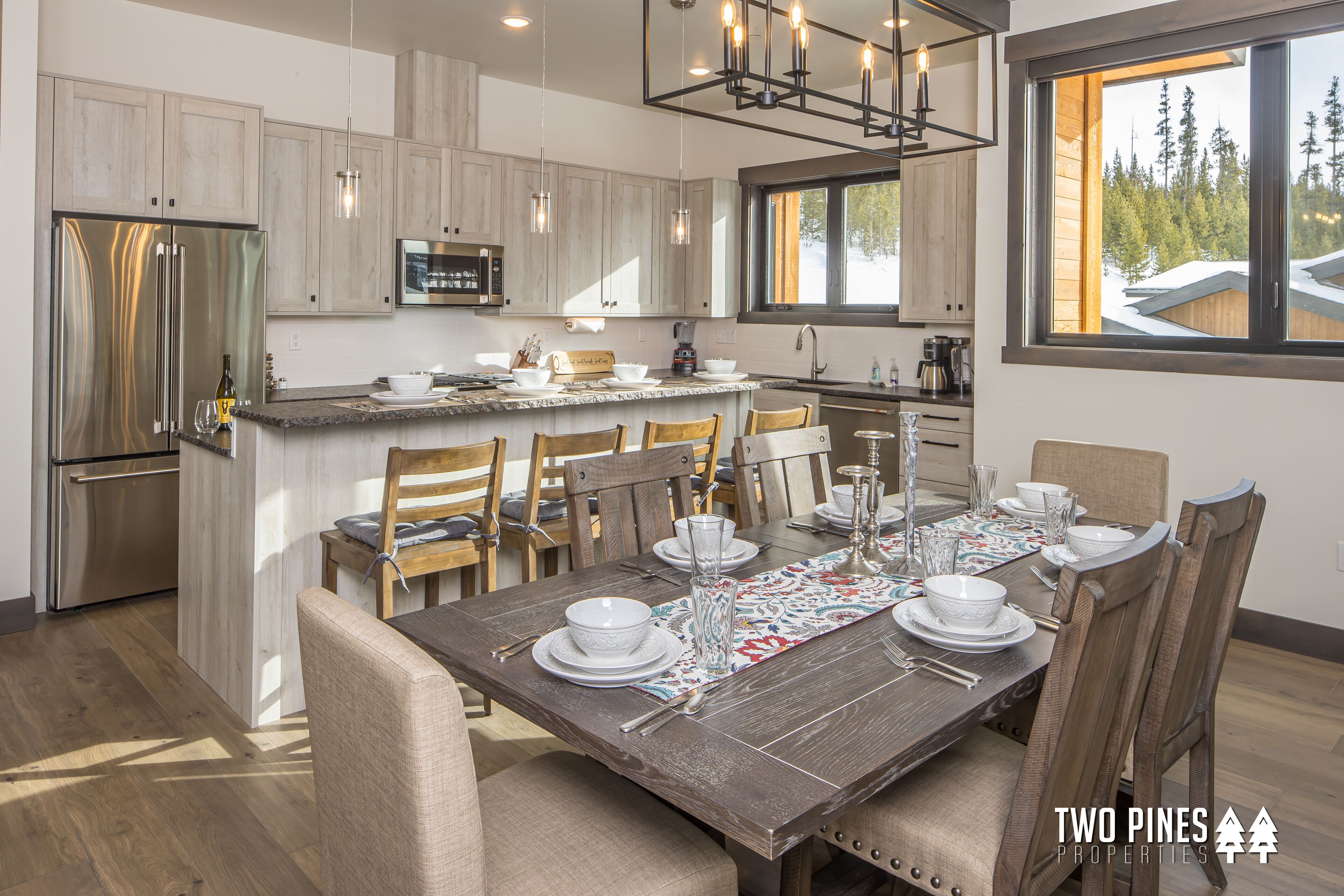 A modern kitchen with wooden cabinets, a stainless steel refrigerator, and a dining area with a wooden table set for six.