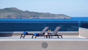 A balcony with two sun loungers, a hat, and two glasses of orange juice.