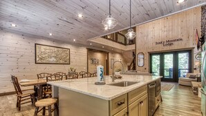 Une cuisine spacieuse dotée d’un grand îlot central, de murs en bois et d’une enseigne indiquant « Soaky Mountain Lodge ».