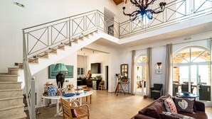 A spacious living area with a staircase, a dining table, and a comfortable seating area.