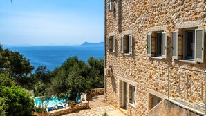 A stone building with a pool and a view of the sea.