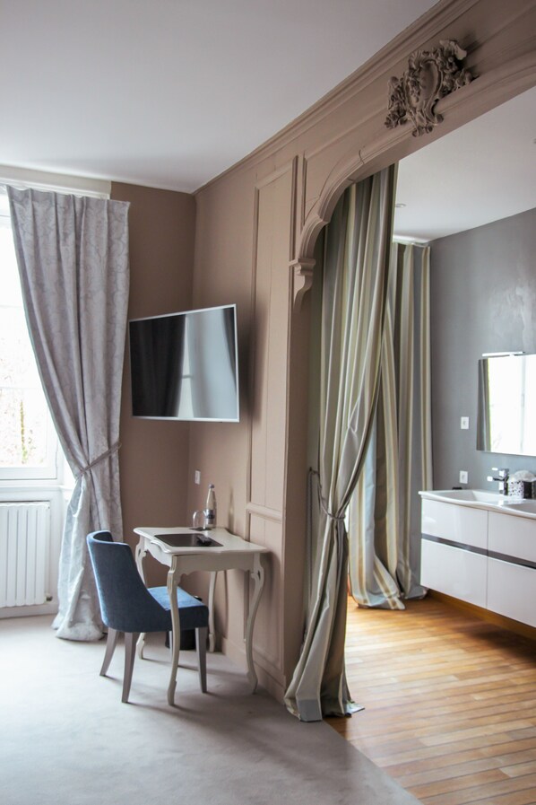 A hotel room with a desk, chair, TV, and a large mirror. -  Le Petit Perier (Laval)
