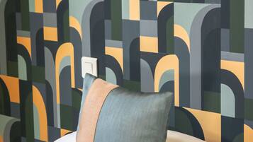 A bed with pillows and a wall with a geometric pattern.