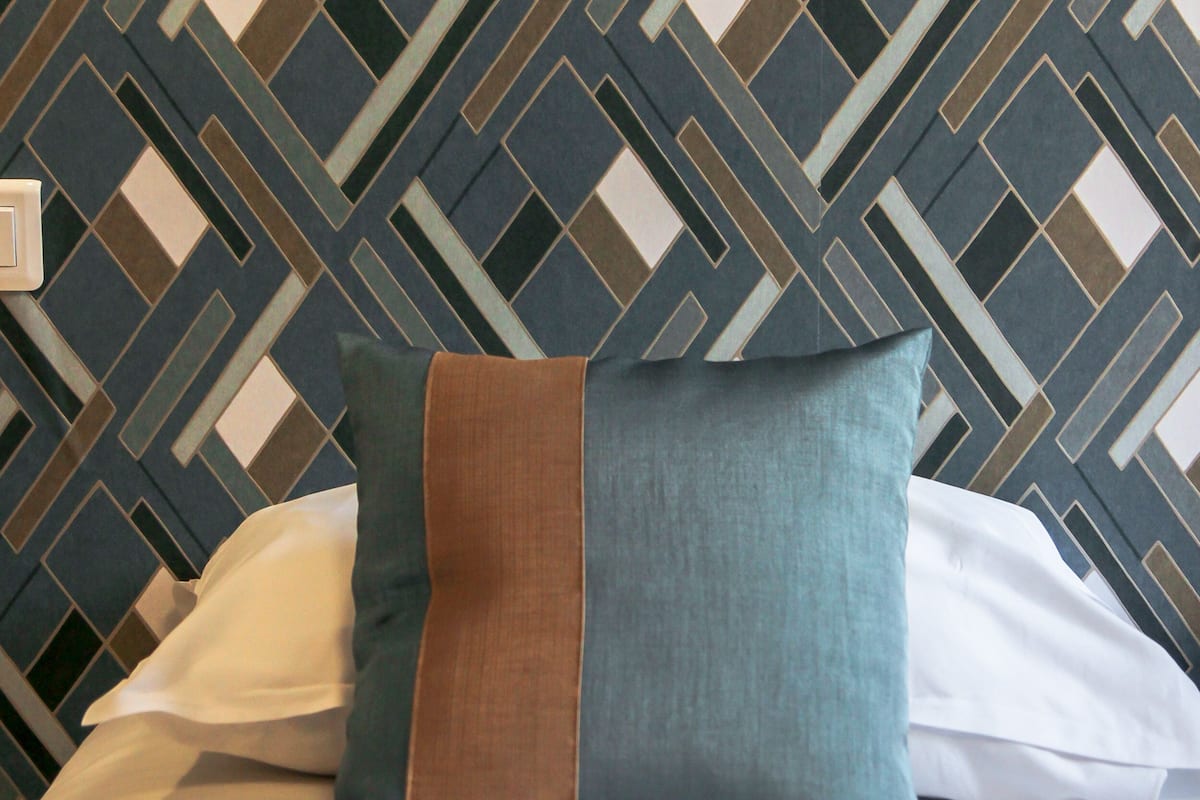 Uma cama com um papel de parede estampado atrás.
