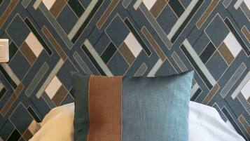 A bed with a patterned wall behind it.