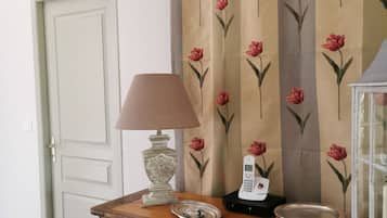 Un meuble en bois sur lequel sont posés une lampe, un téléphone et une assiette décorative.