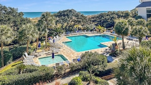A resort with a large pool, sun loungers, and palm trees. - Shipwatch C317: Oceanfront Escape in Wild Dunes – Your Cozy Island Retreat (Isle Of Palms)