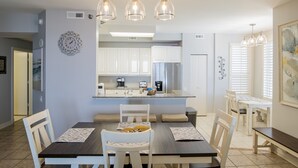 Una cocina moderna con armarios blancos, una isla central e iluminación colgante.