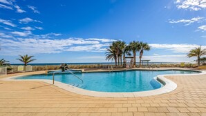 Una piscina de borde curvo, palmeras y vista al océano.