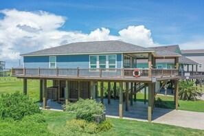 A two-story building with a balcony and a covered walkway. - The Neon Moon 3 Bedroom Home by RedAwning (Port Bolivar)