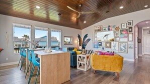 Une cuisine moderne avec un îlot central en bois, des chaises bleues et un fauteuil jaune.