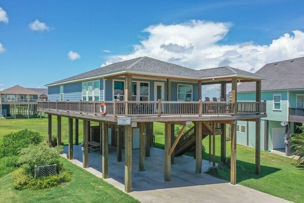 A waterfront property with a covered deck and a staircase leading to a second level. - The Neon Moon 3 Bedroom Home by RedAwning (Port Bolivar)