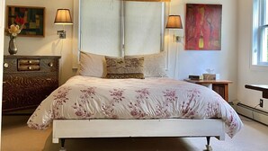 A bedroom with a large bed, two bedside lamps, a wooden headboard, a decorative pillow, a dresser, a painting, and a window. - the suite @ barn & bike - private, bucolic, serene setting (Red Hook)