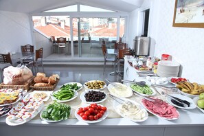 Una mesa de buffet con diversos alimentos y vistas a la ciudad a través de amplios ventanales.