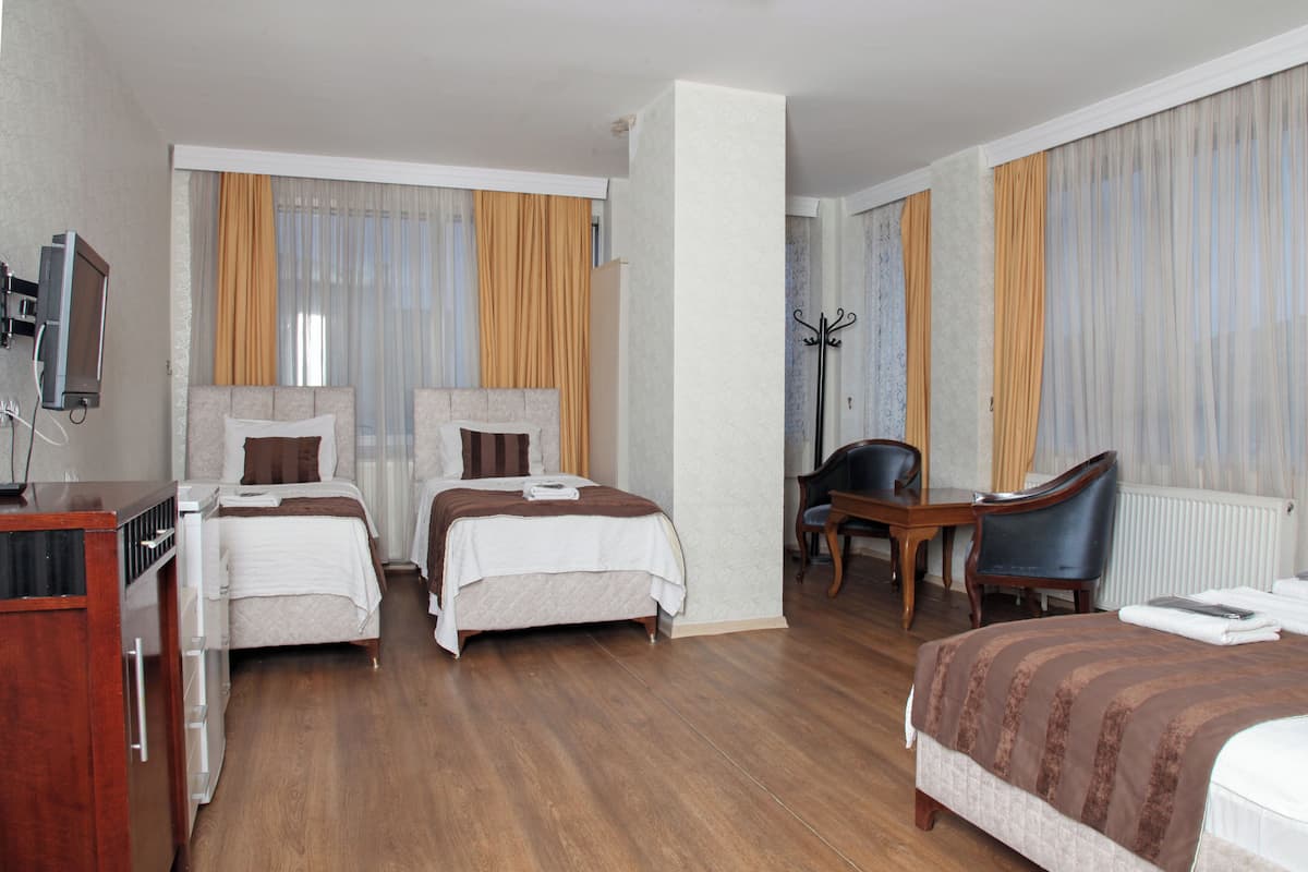 Quarto de hotel com duas camas, uma escrivaninha, uma cadeira e uma televisão.