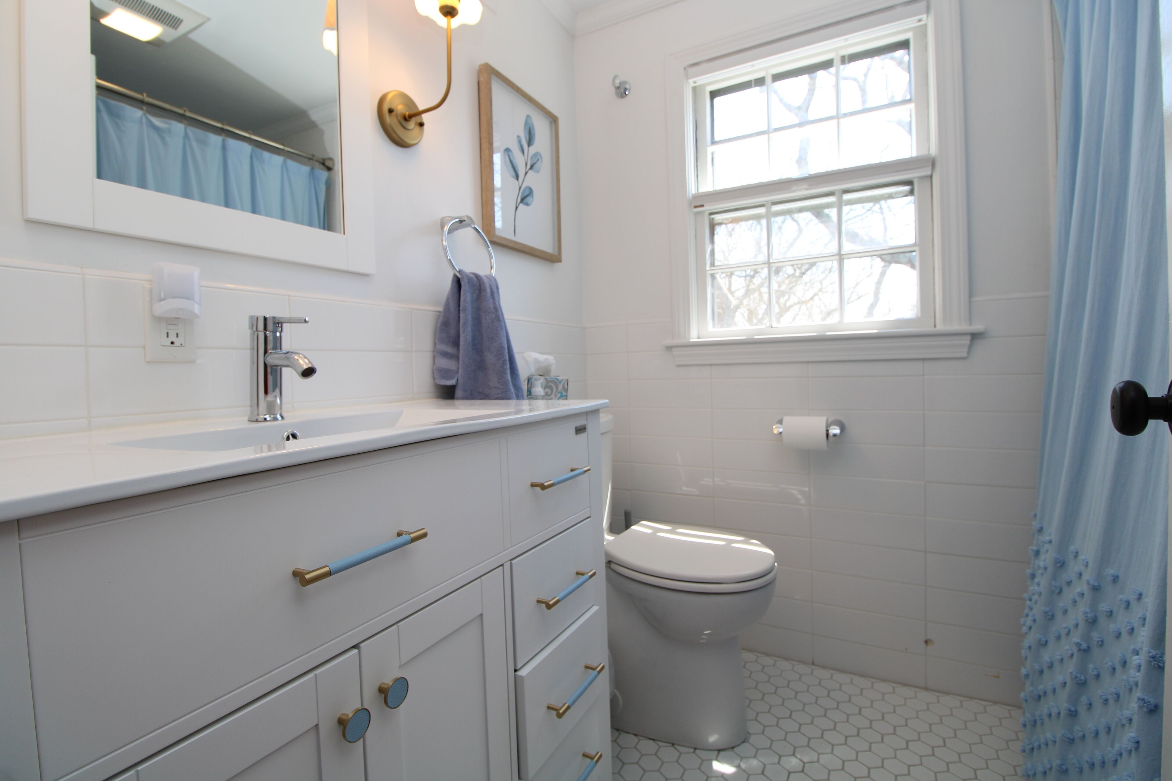 A bathroom with a white sink, a toilet, and a window with a curtain.