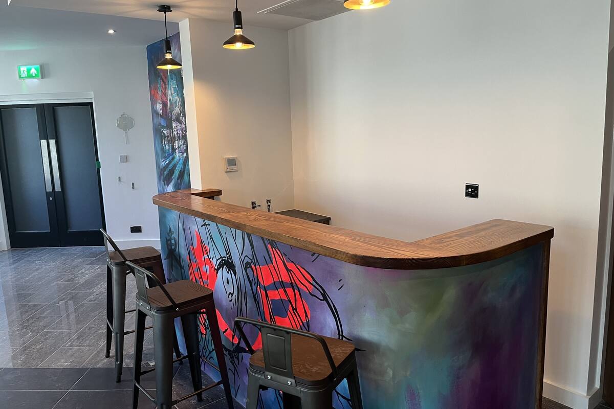 A reception area with a wooden counter, bar stools, and a colorful abstract mural.