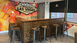 A bar area with a 'Welcome to Fabulous Las Vegas Nevada' sign, bar stools, and a window with a view of the outside. - The Bling Hotel by UStay (Liverpool)