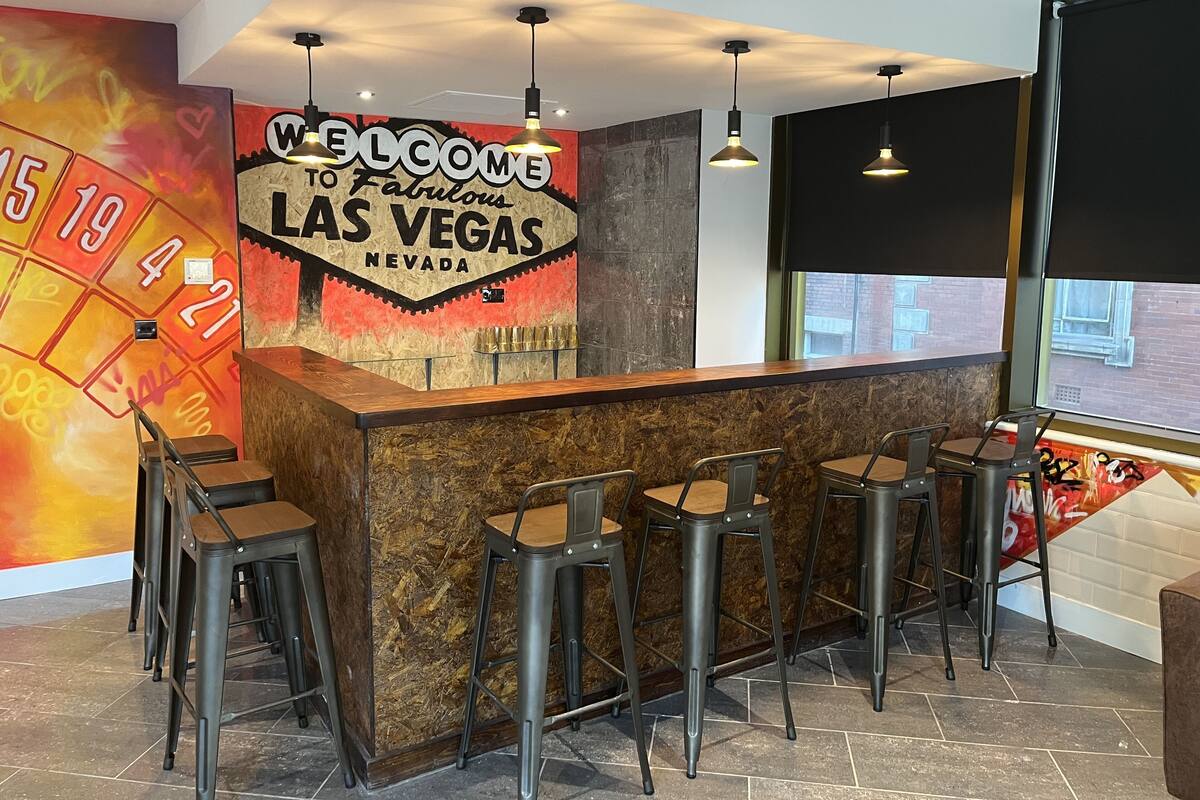 A bar area with a 'Welcome to Fabulous Las Vegas Nevada' sign, bar stools, and a window with a view of the outside.