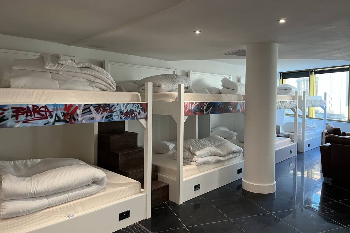 A hotel room with bunk beds, a staircase, and a view of the outside.