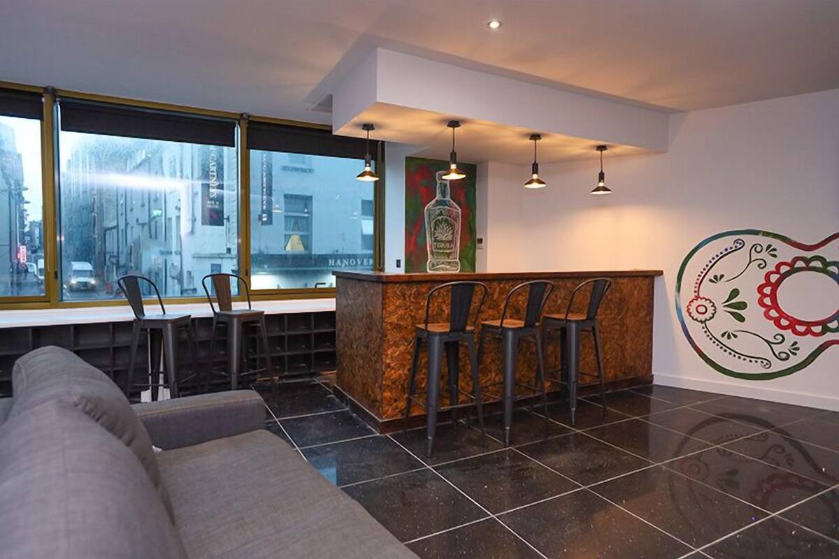 A modern bar area with a counter, bar stools, and pendant lighting.