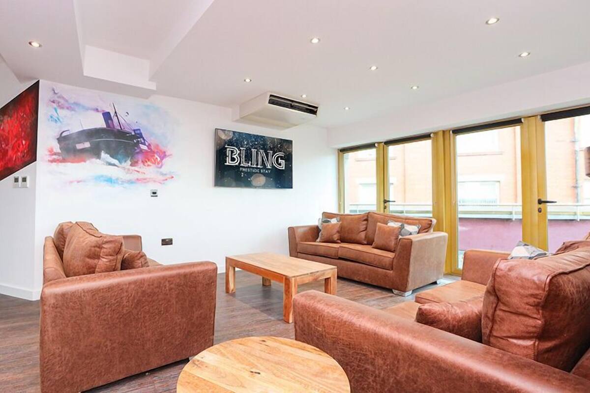 A modern living room with leather sofas, a wooden coffee table, and a large wall art piece.