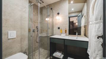 A modern bathroom with a glass-enclosed shower, a white sink, and a large mirror.