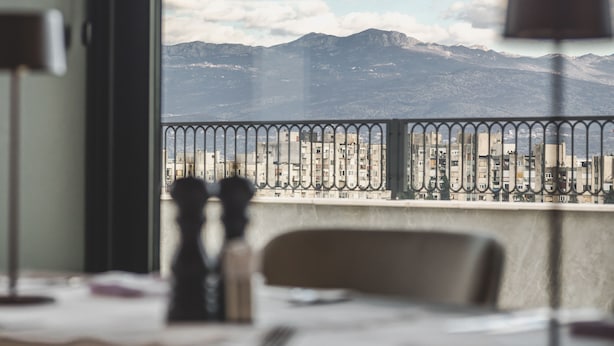 Et hotelværelse med udsigt til bjerge og en balkon med gelænder.