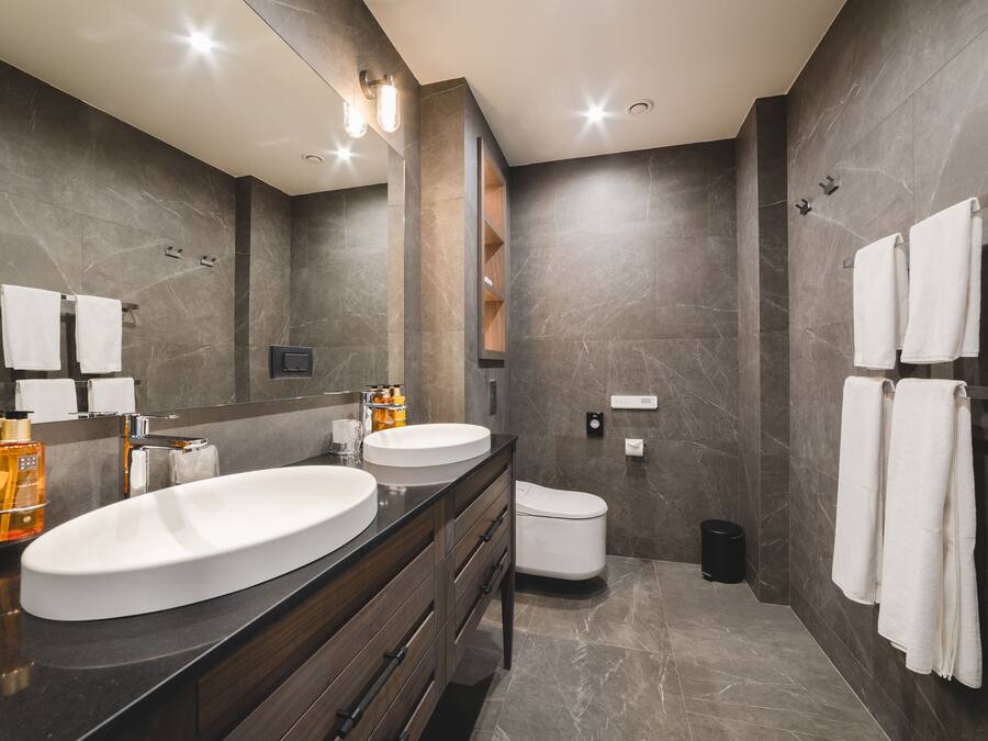 A modern bathroom with two sinks, a toilet, and a shower area.