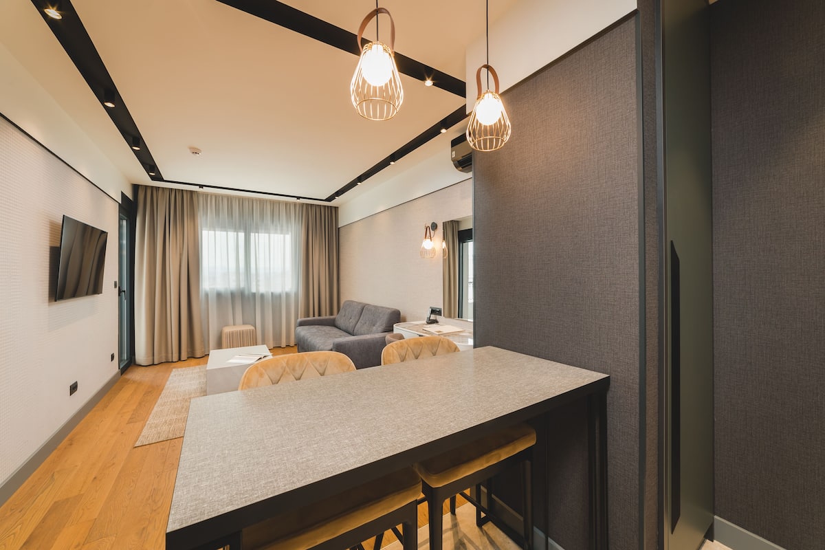 Ein modernes Wohnzimmer mit Essbereich, einer Couch und einem an der Wand befestigten Fernseher.