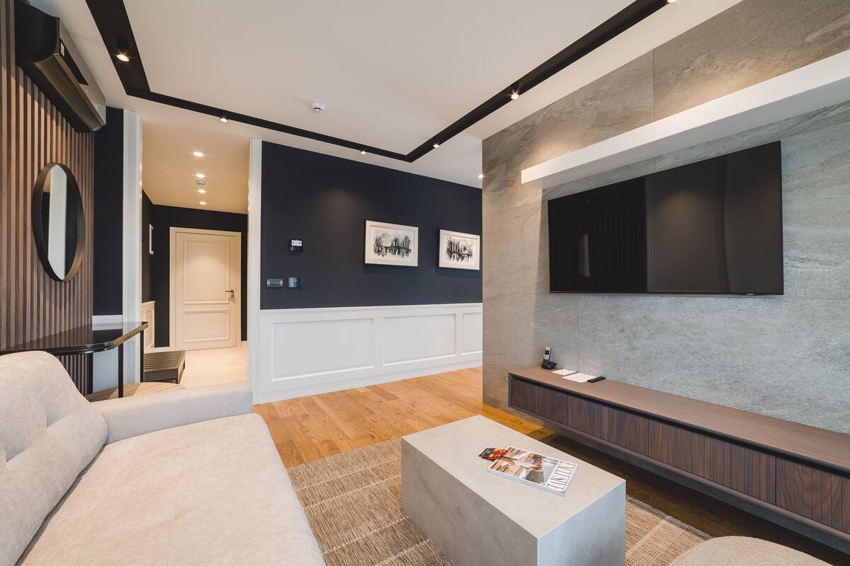 Ein modernes Wohnzimmer mit einer Couch, einem Couchtisch und einem flachbildfernseher an der Wand.
