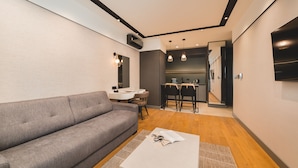 En moderne stue med en grå sofa, et hvidt sofabord og et spiseområde med et lille bord og stole.
