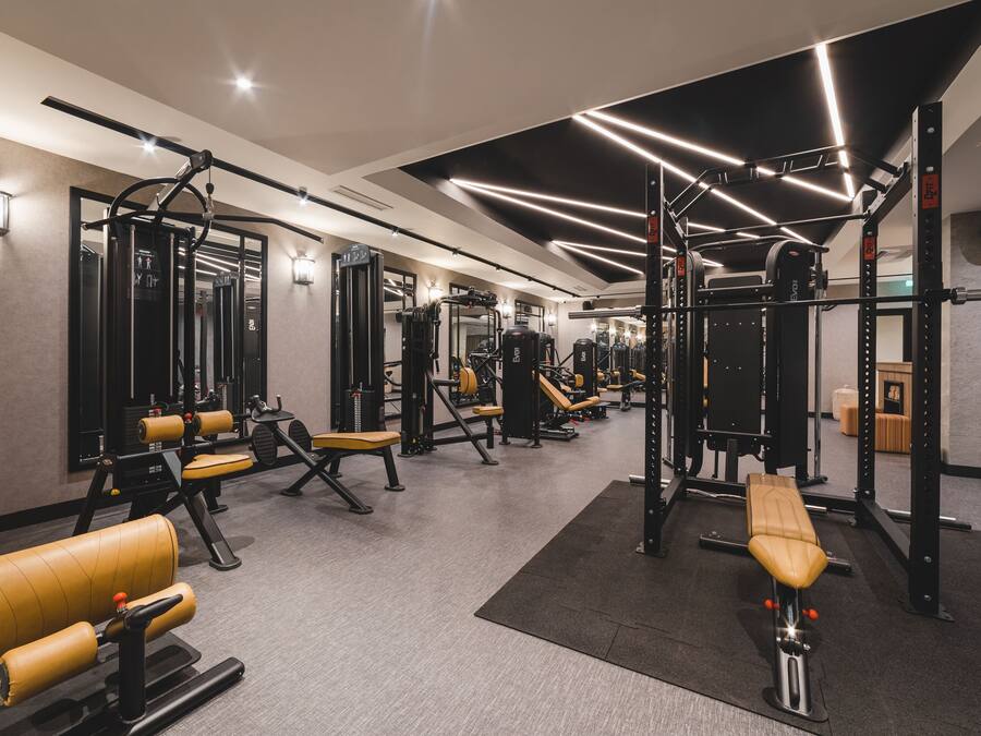 A modern gym with various exercise equipment, including weight machines and benches.