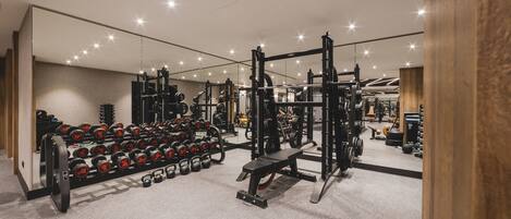 A gym with weightlifting equipment, benches, and dumbbells.