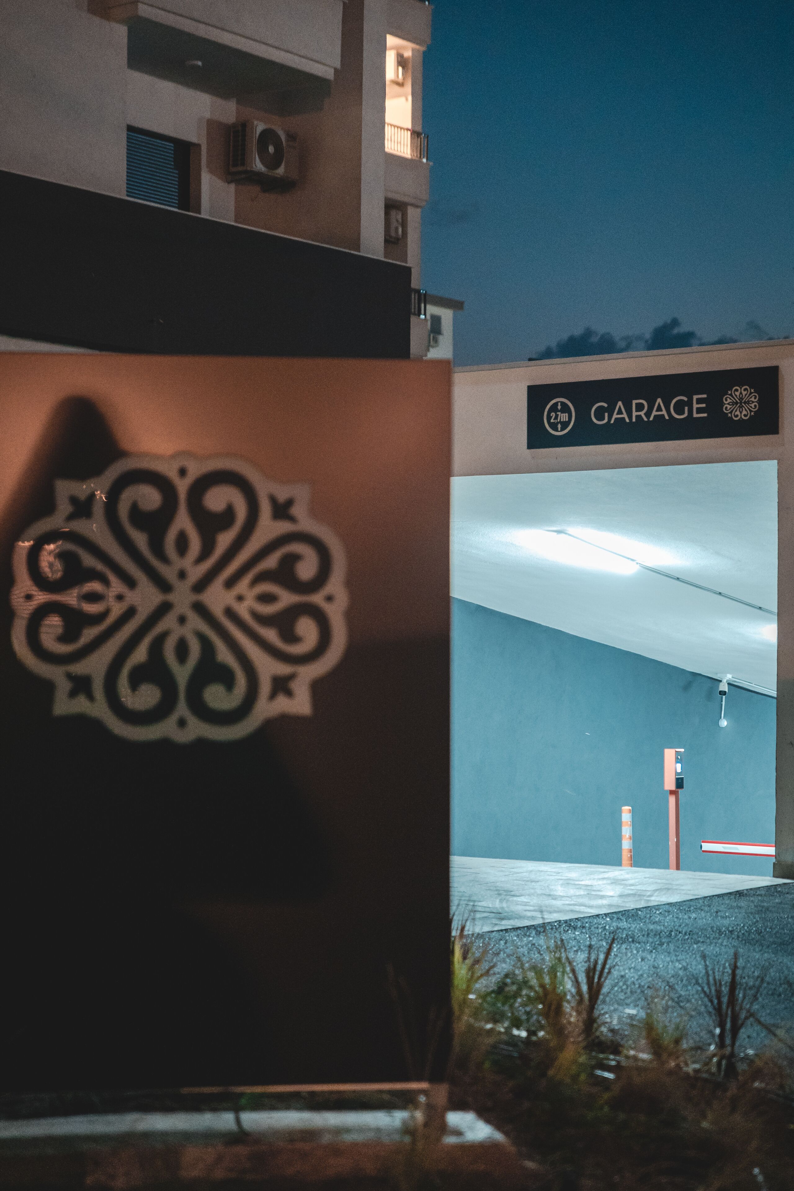 A building entrance with a decorative emblem, a garage sign, and a blue wall.